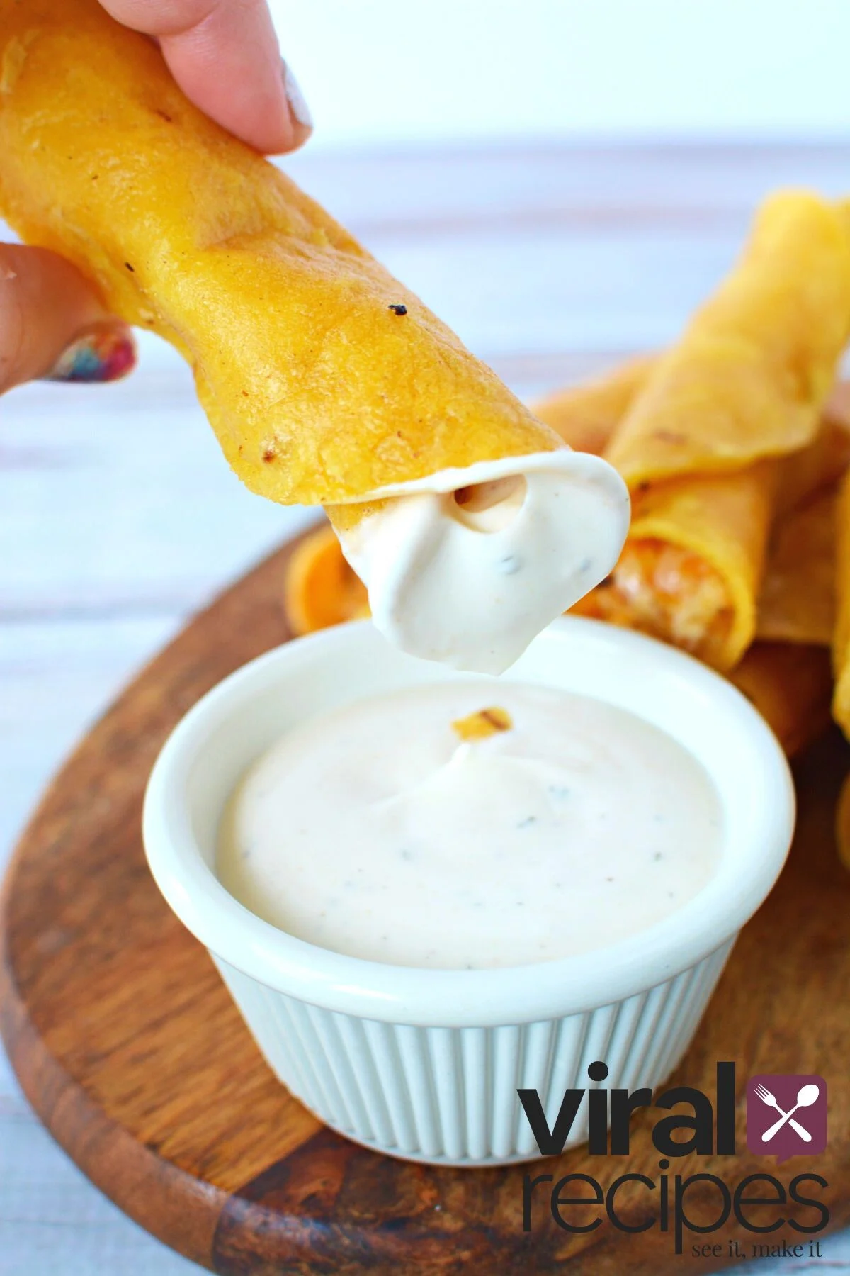dipping taquitos in a ranch dipping sauce.