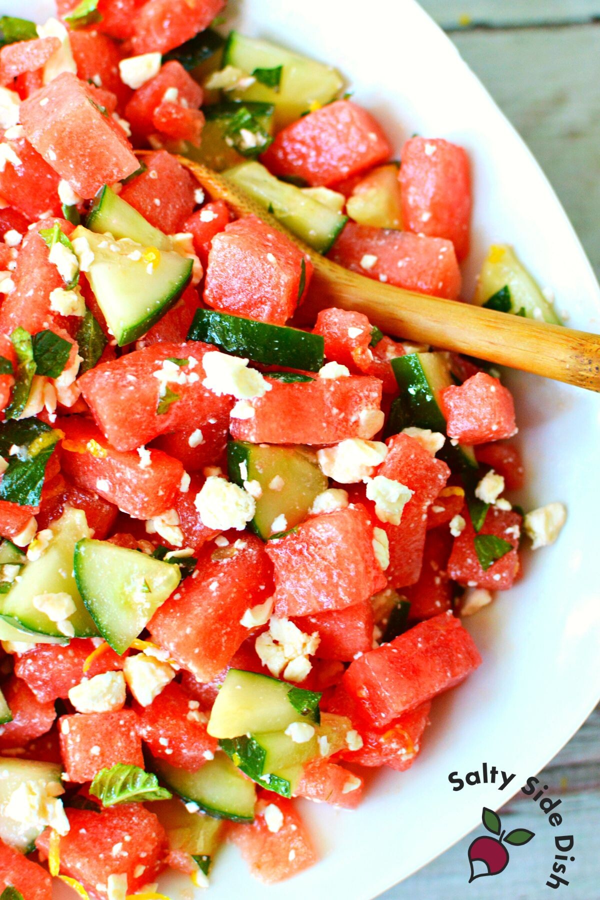 large bowl of watermelon salad and wooden spoon.
