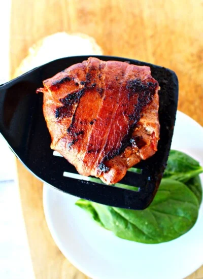 bacon wrapped tomato slices on a spatula.