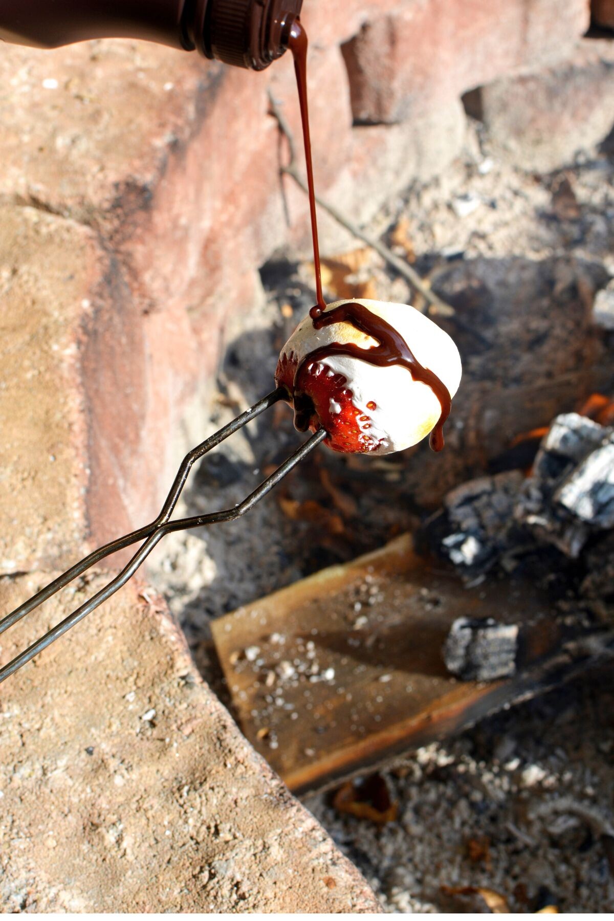 smothering marshmallow strawberries with chocolaty sauce.