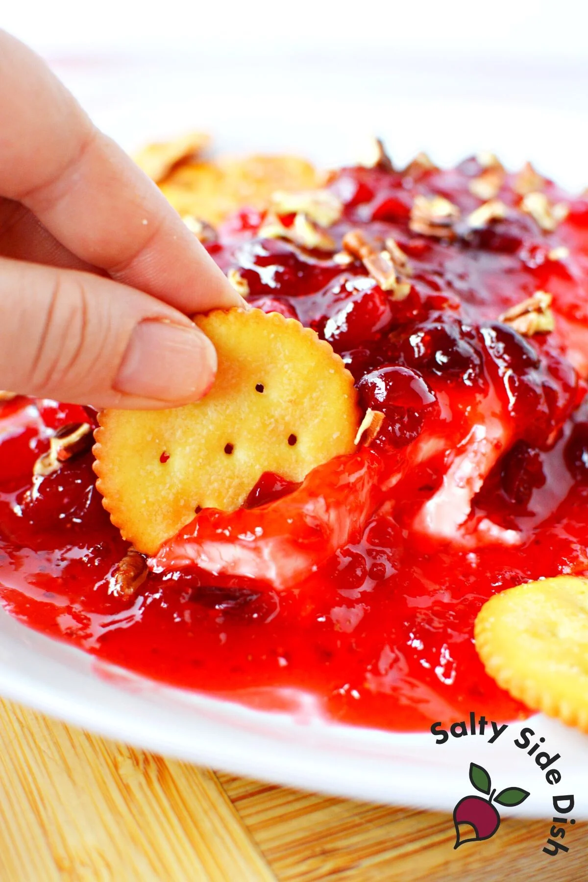 dipping ritz cracker into cream cheese dip.