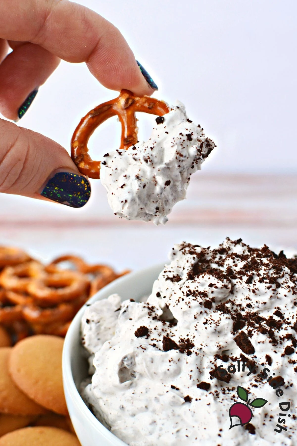 viral dip recipe with oreos and whipped cream being dipped with a pretzel.