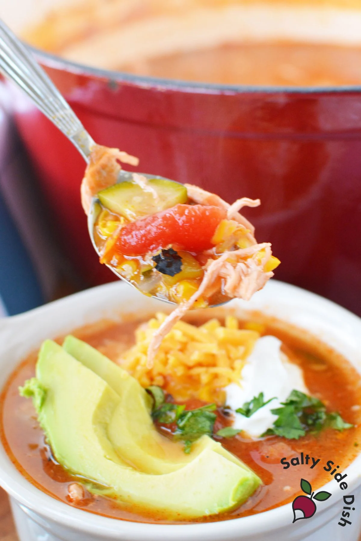 taco soup with toppings like cheese, avocado, and sour cream.