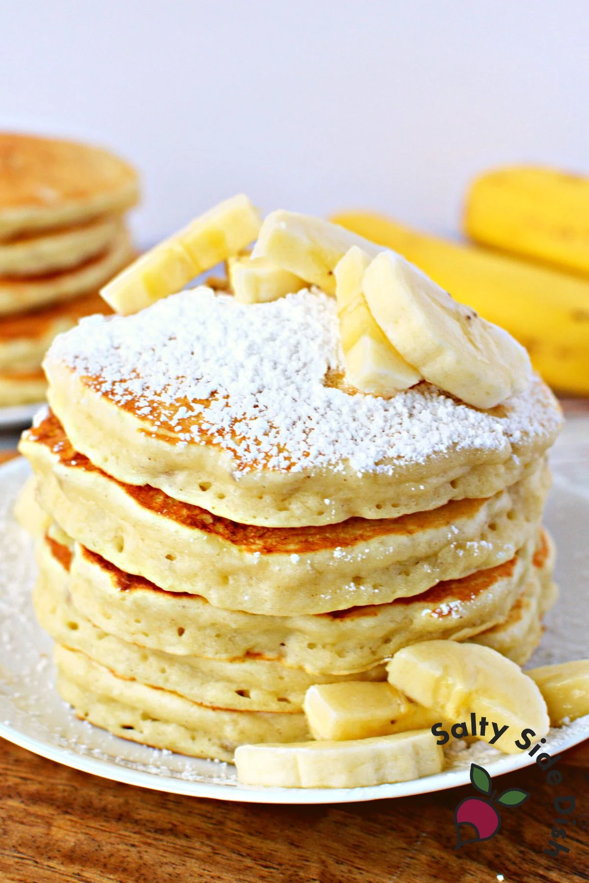 banana pancakes recipe stacked high with extra bananas.