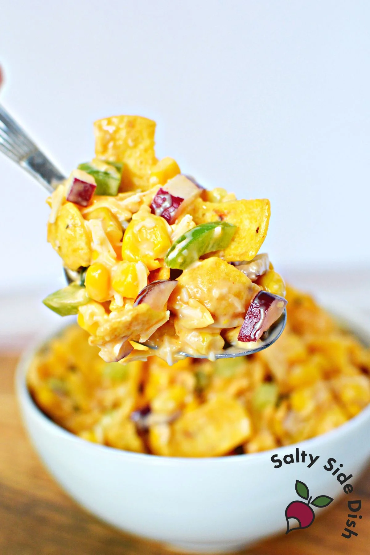 corn salad with fritos on a spoon.