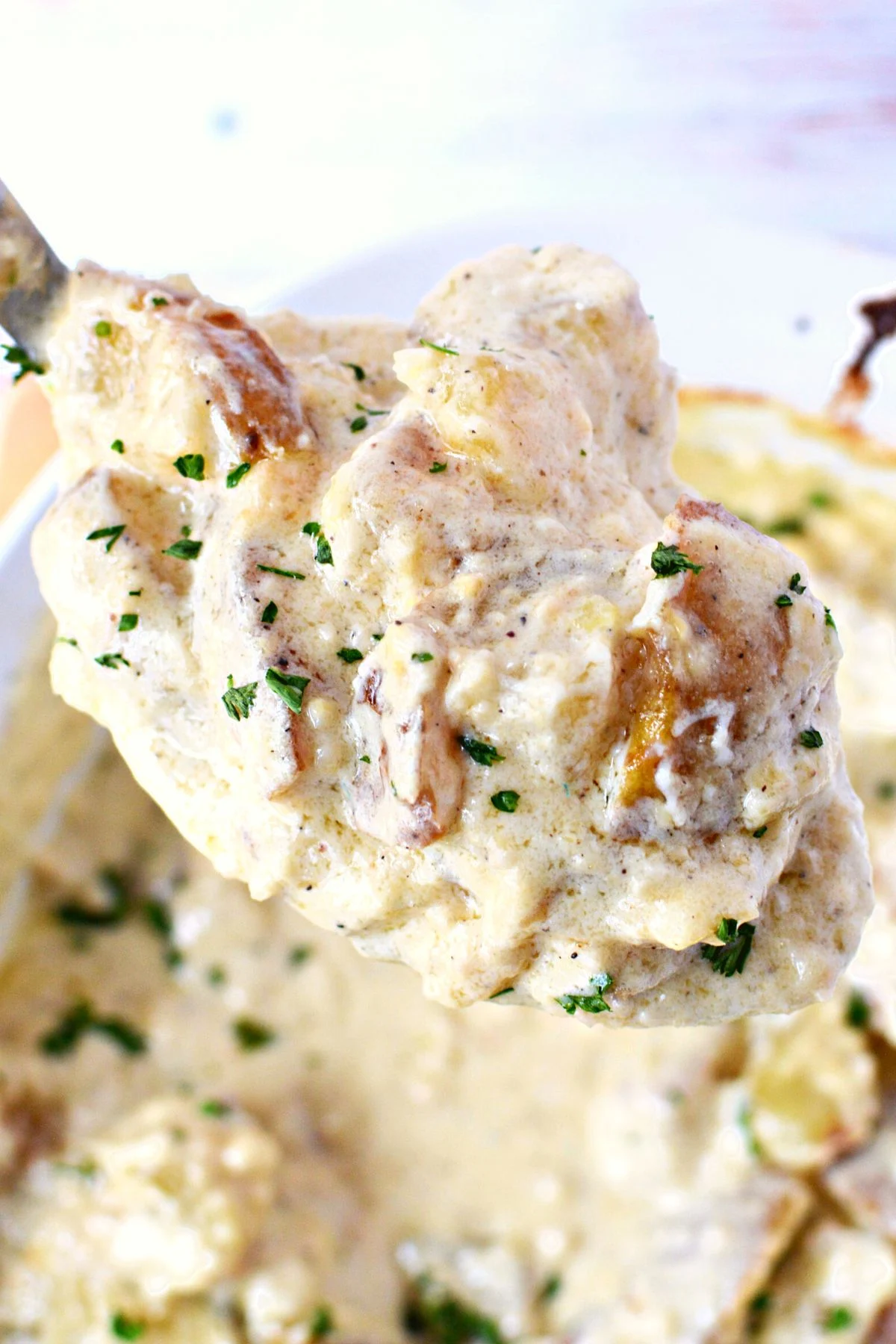 how to make creamy alfredo potatoes sitting on a serving spoon.