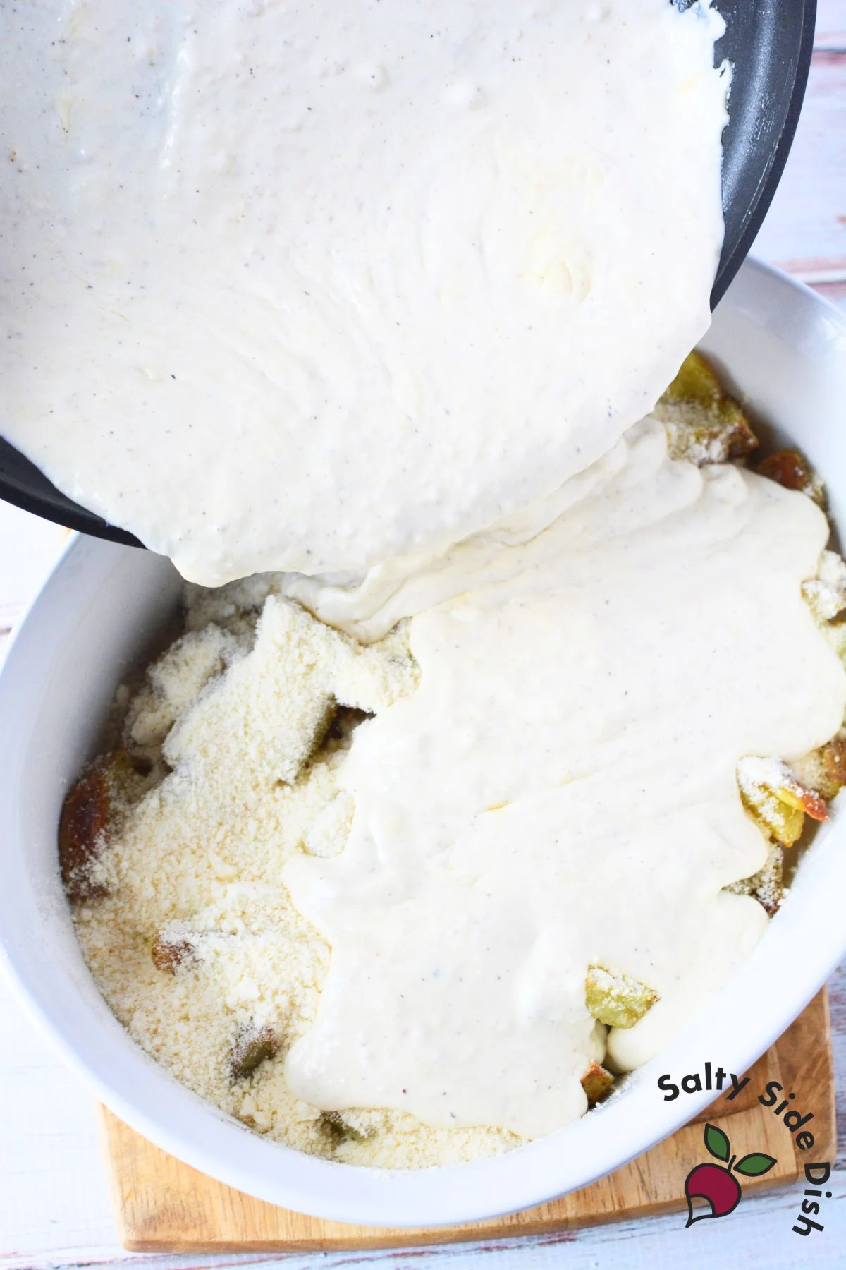 pouring alfredo sauce over roasted potatoes.