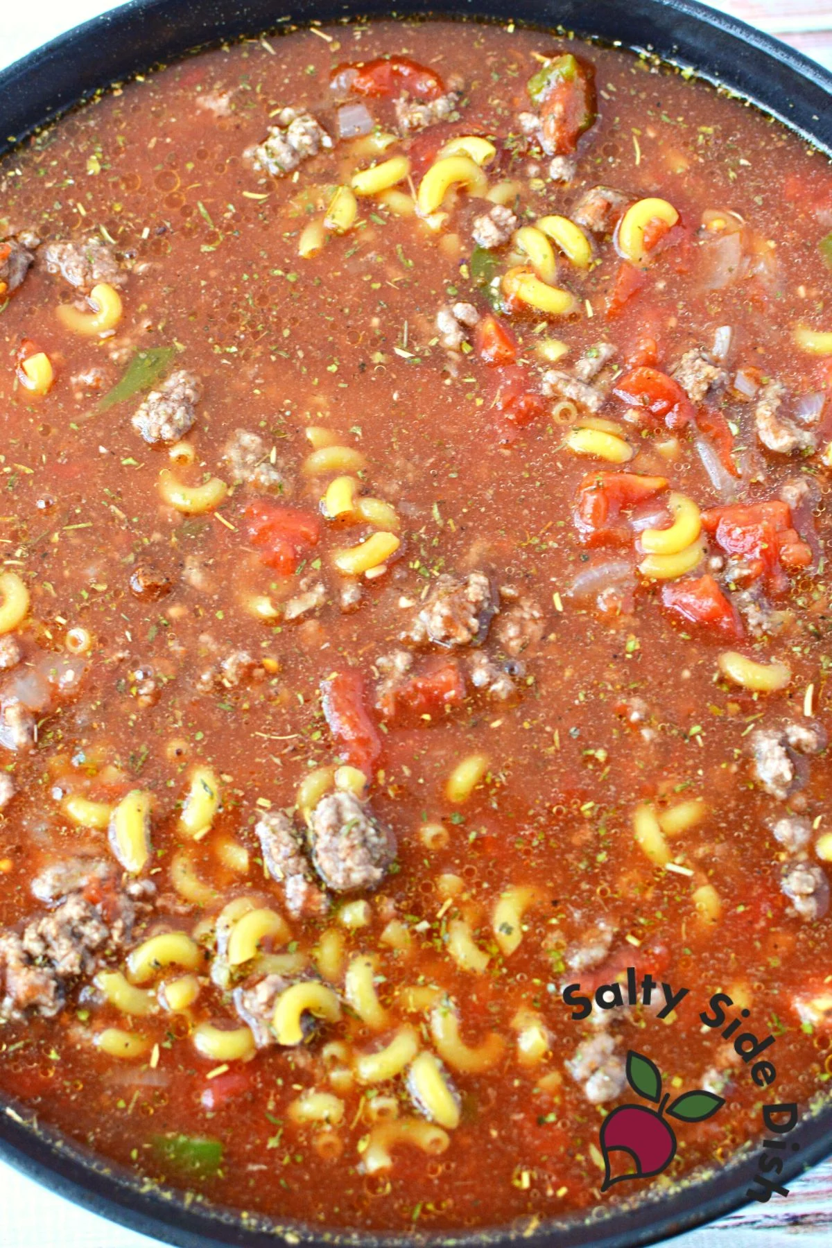mixed together all ingredients for homemade beefaroni in a cast iron pan.