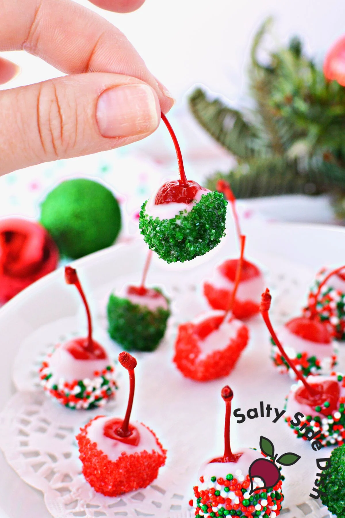 holding a cherry stem of a vodka soaked and chocolate covered christmas cherry.