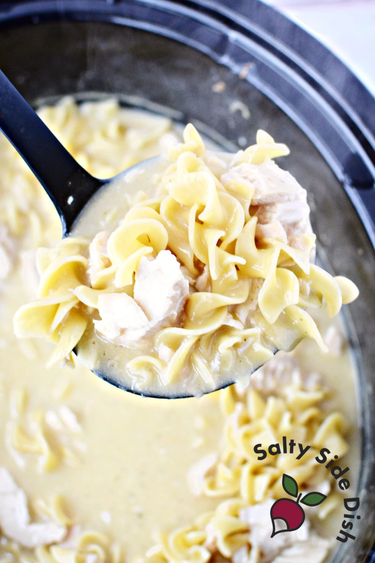 ladle scooping out noodles, cooked chicken, and homestyle gravy.