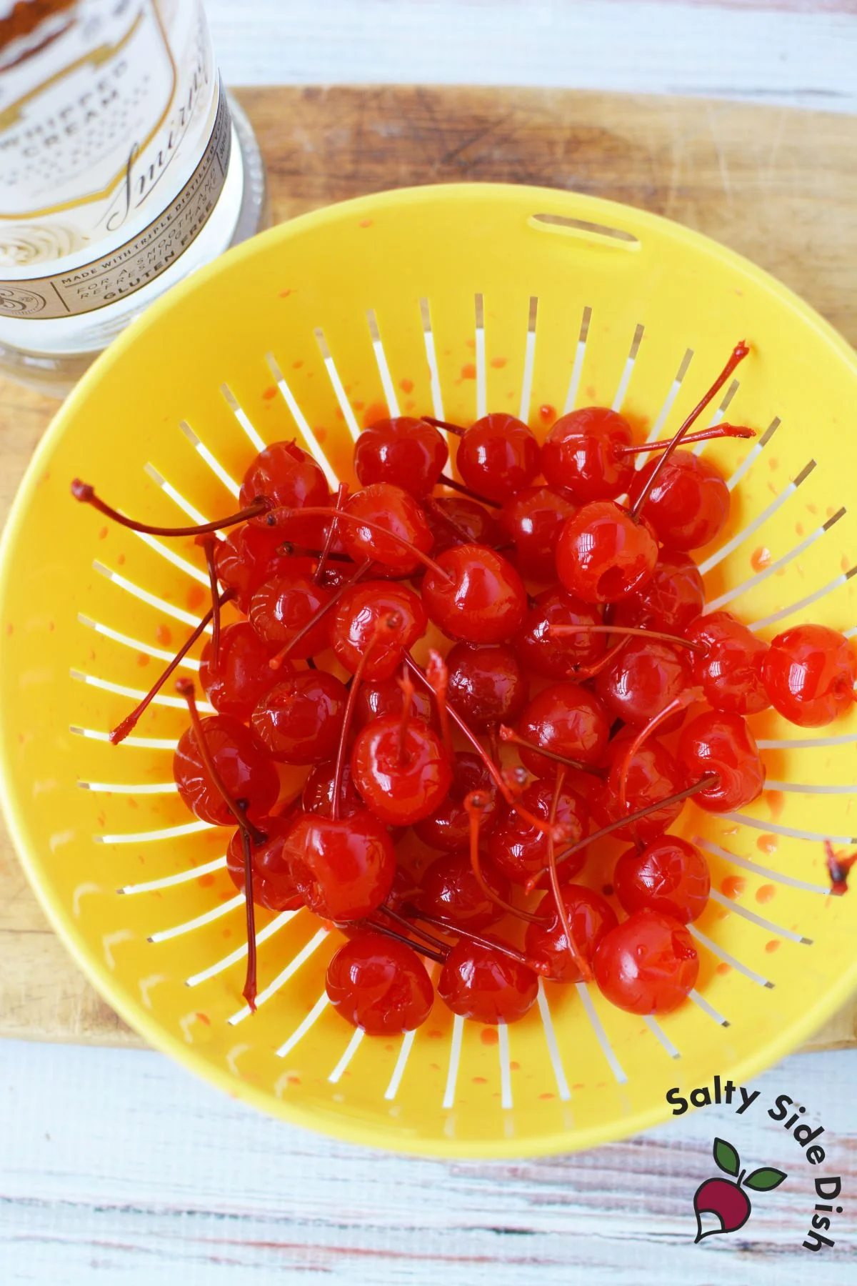 long stemmed cherries in a yellow colander.