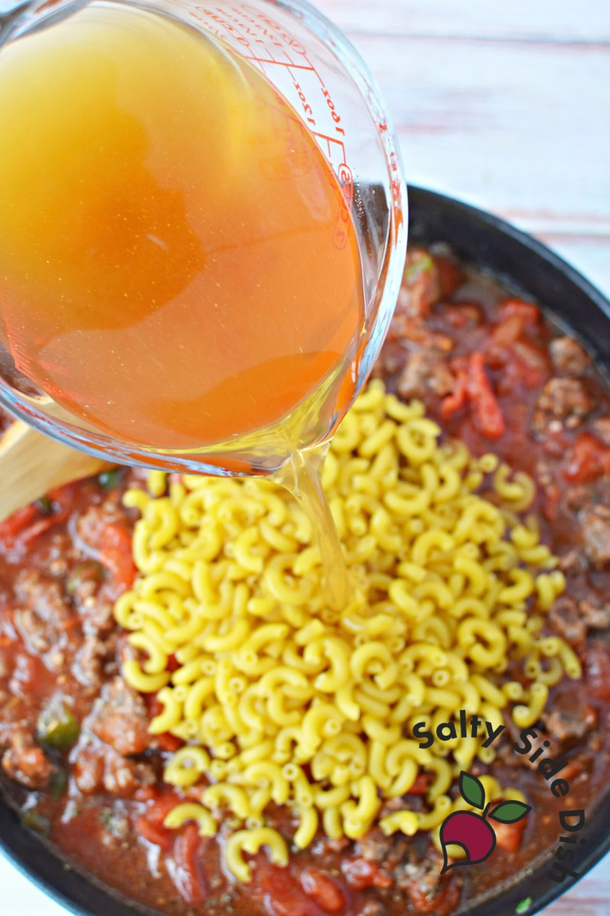 adding chicken broth and dry macaroni noodles to pan.