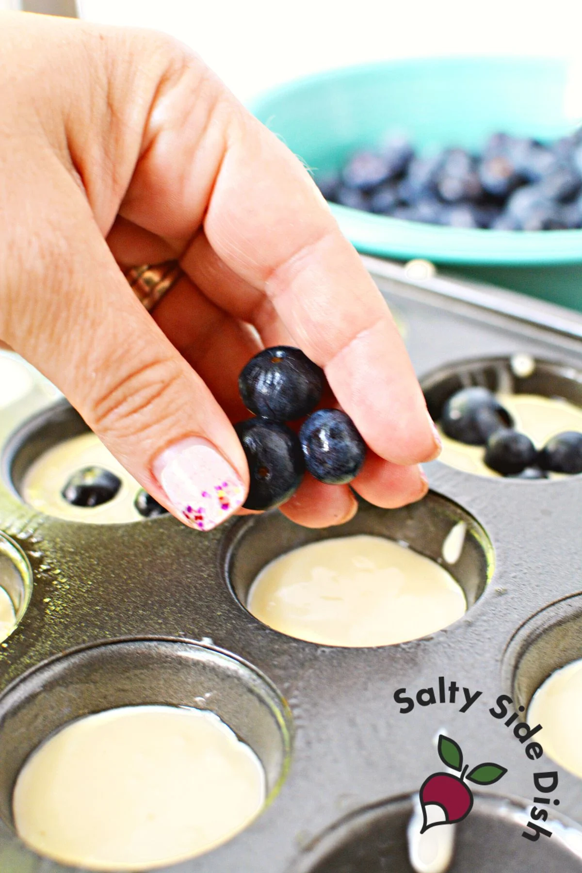 adding fresh blueberries to a muffin tin.