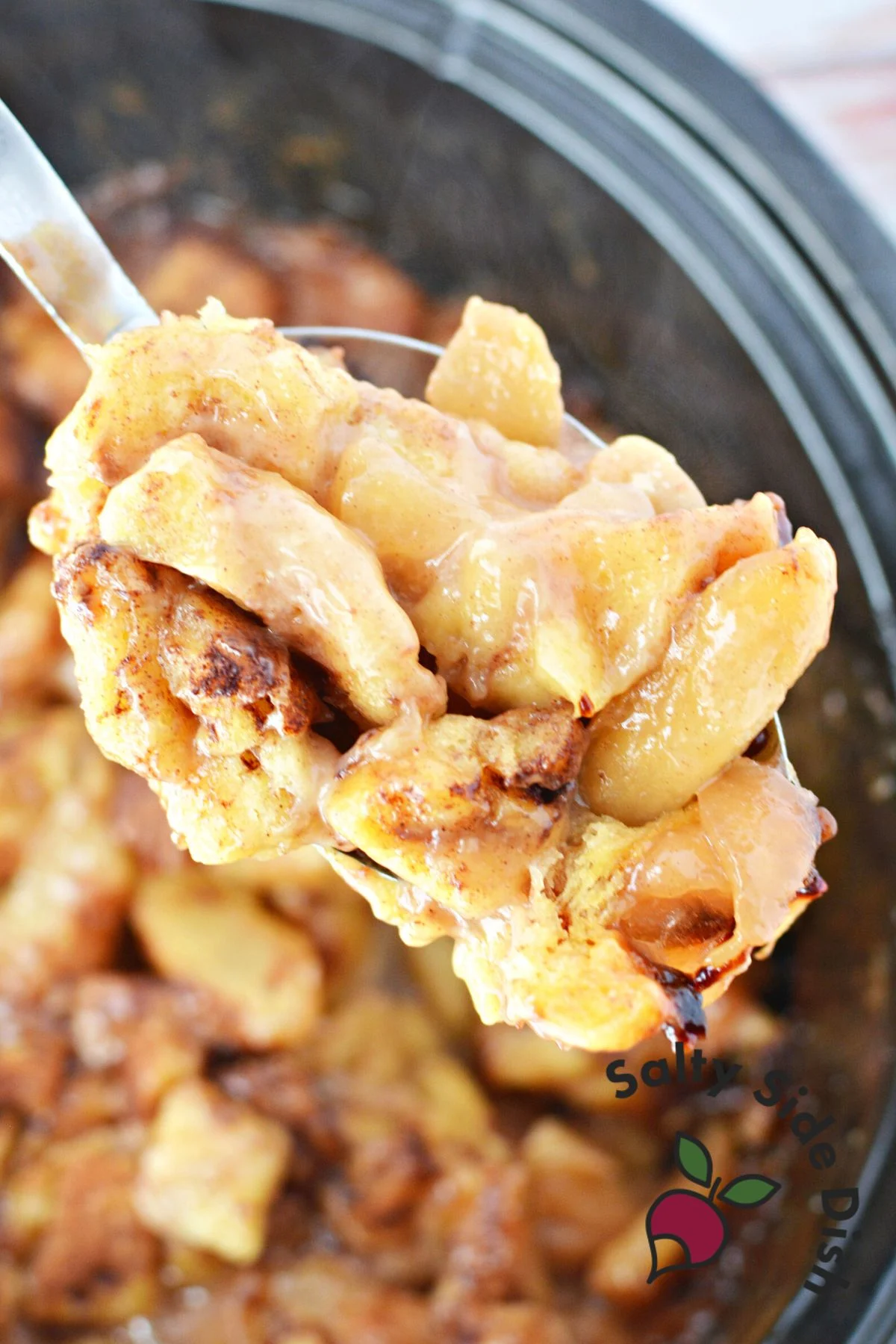 silver spoon holding a scoop of cinnamon rolls out of crockpot.
