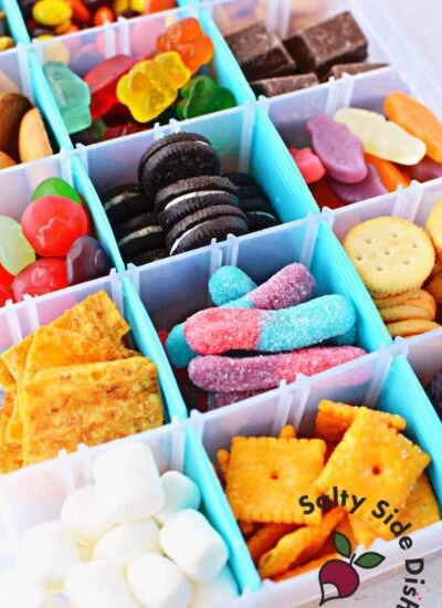 a picture of a snack box with a variety of candy and salty snacks inside each compartment.