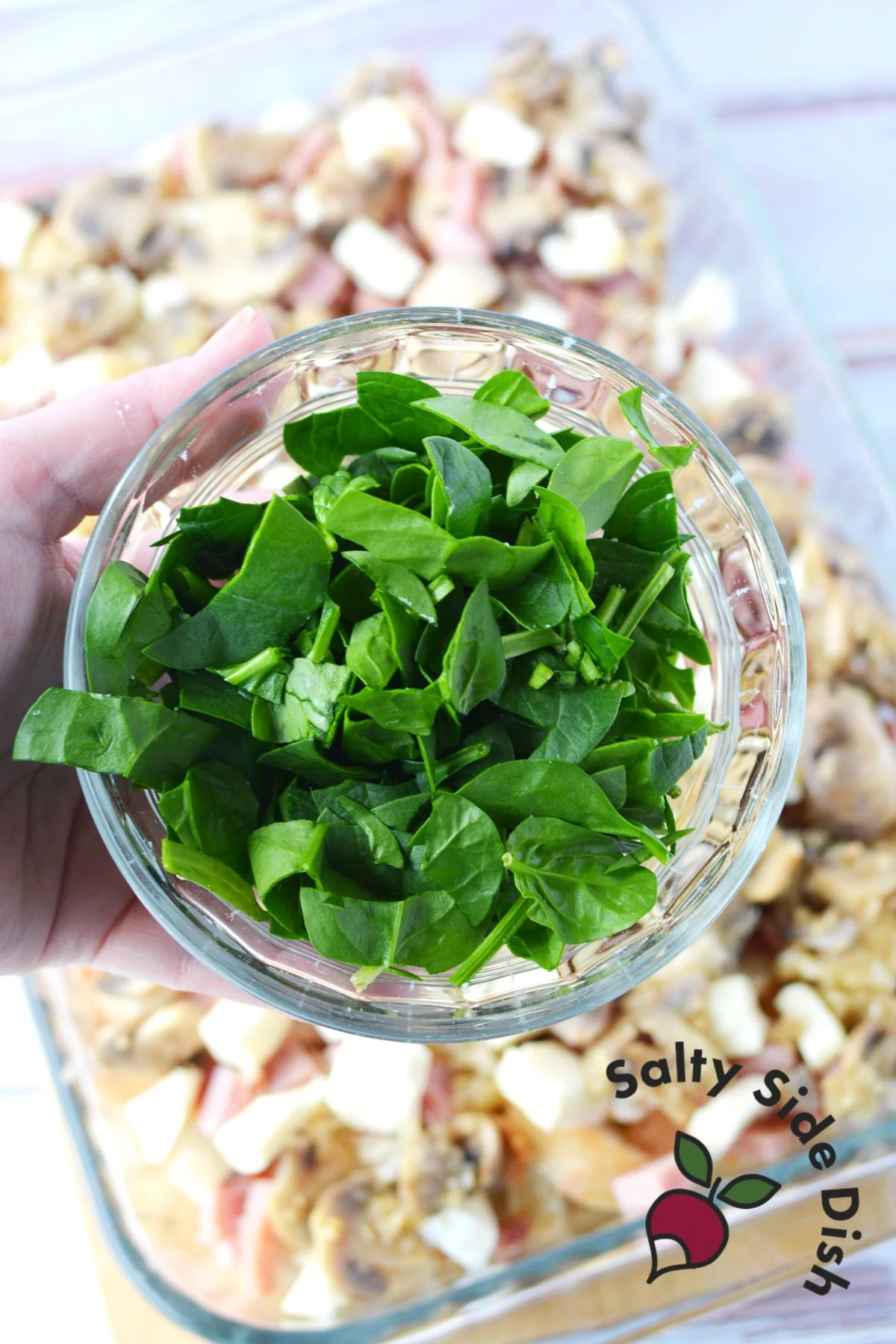 adding fresh spinach to casserole dish.