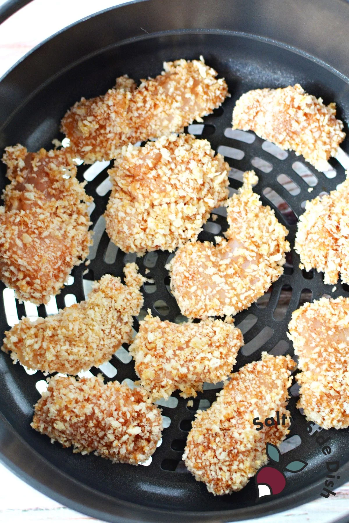 adding coated and crumbed chicken bites to air crisp basket.