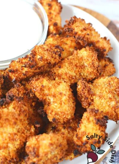 pile of popcorn chicken on a plate with ranch dressing.