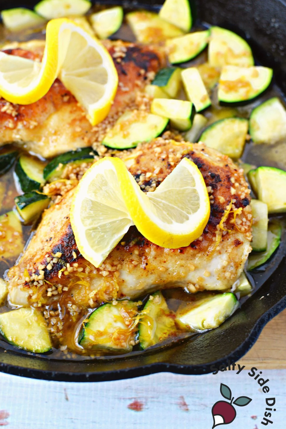 glazed chicken sitting on zucchini with lemon on top.