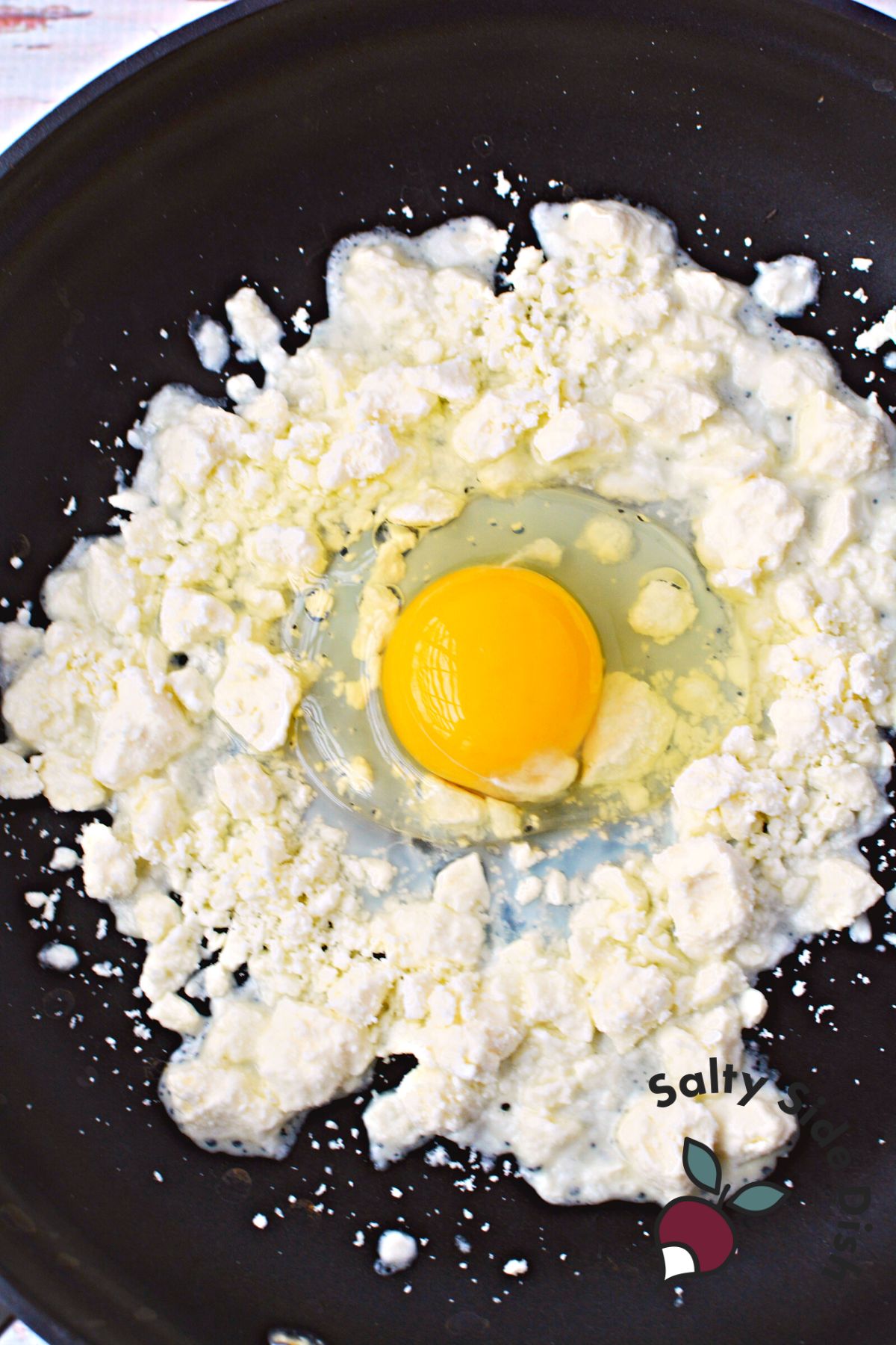 egg cracked in the center of feta cheese.