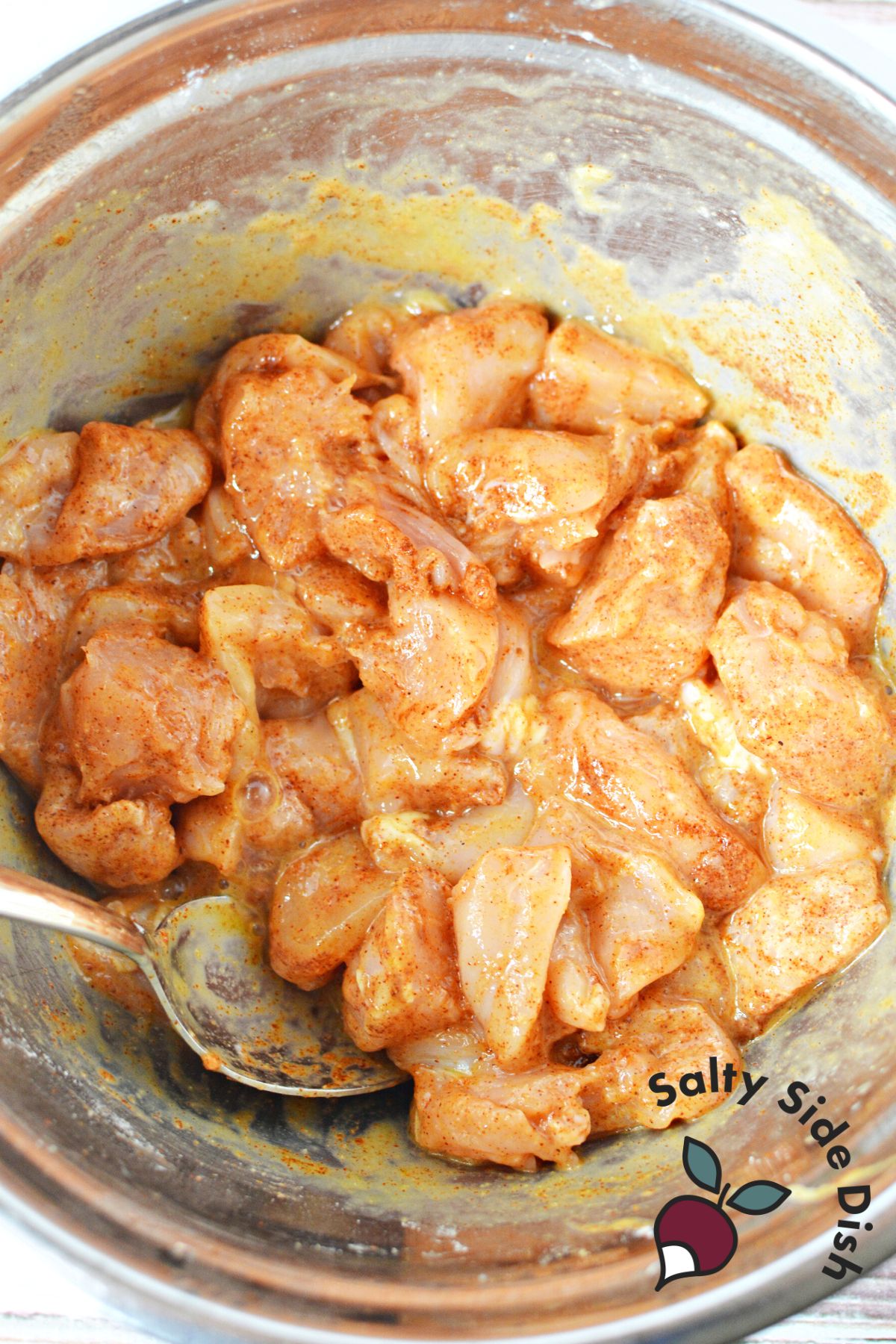 chicken bites in a silver mixing bowl marinating.