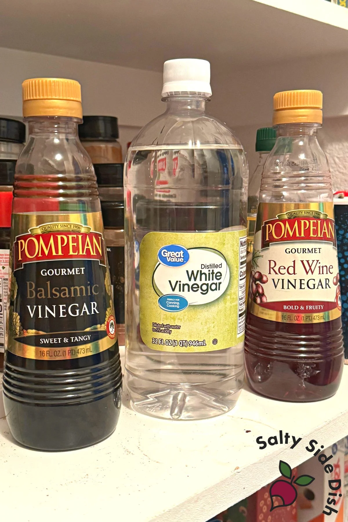 3 bottles of vinegar on a shelf.