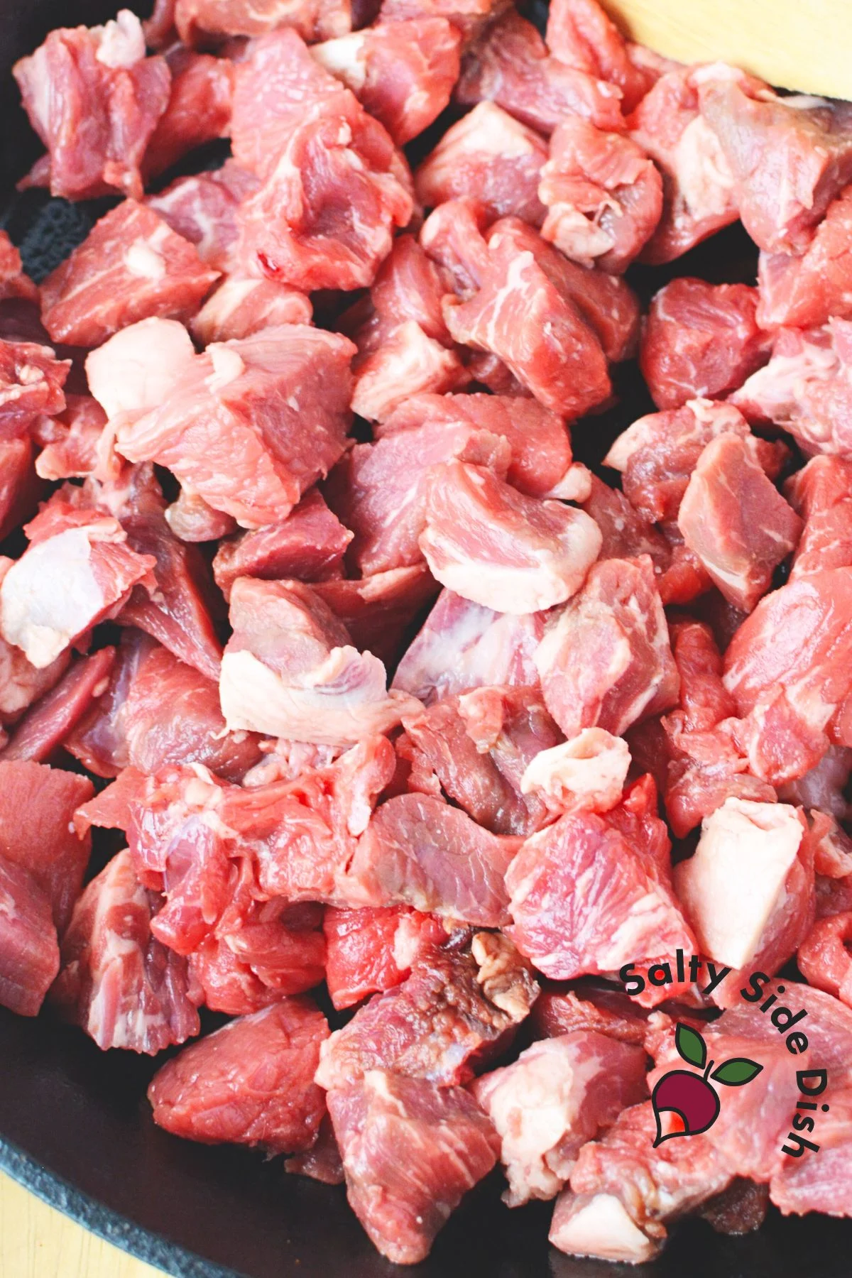 chunks of beef pieces in a cast iron pan.