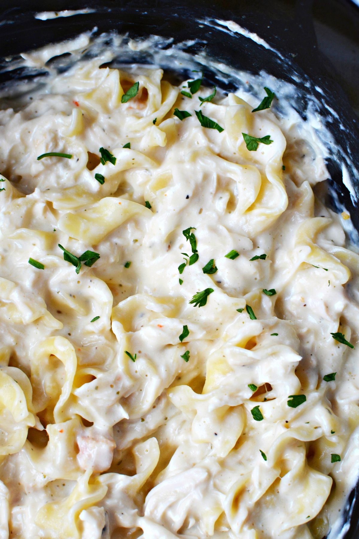 creamy chicken in a black crockpot.