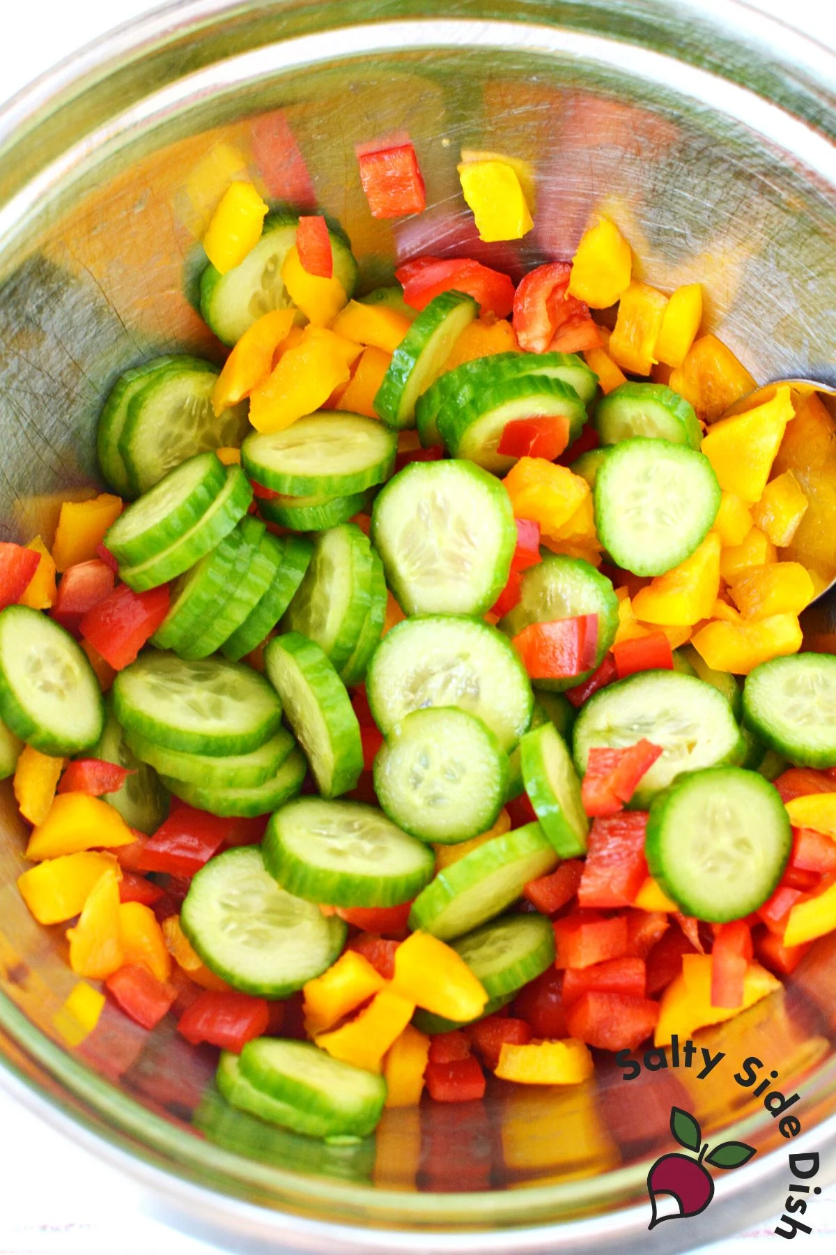 cucumber and bell peppers in a silver mixing bowl.