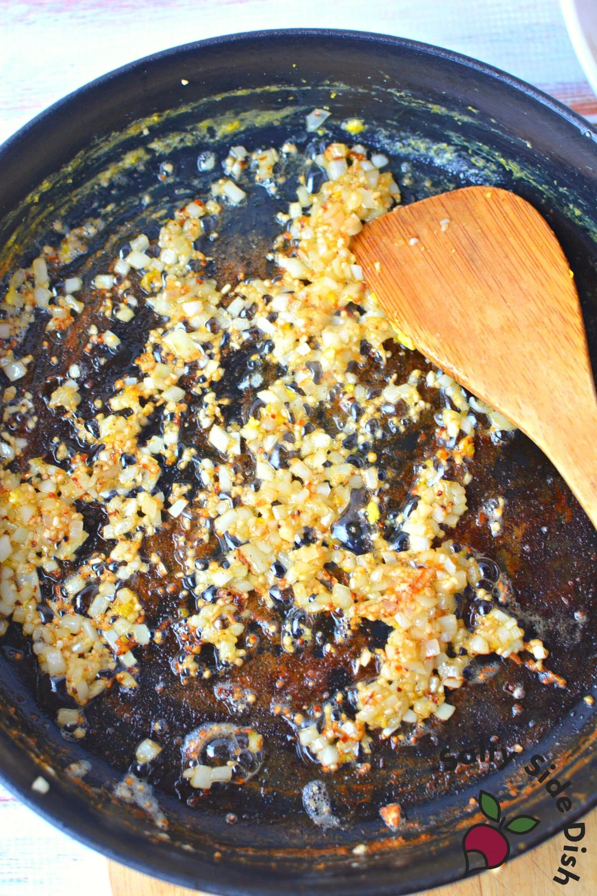 stirring garlic and onions in a cast iron pan.