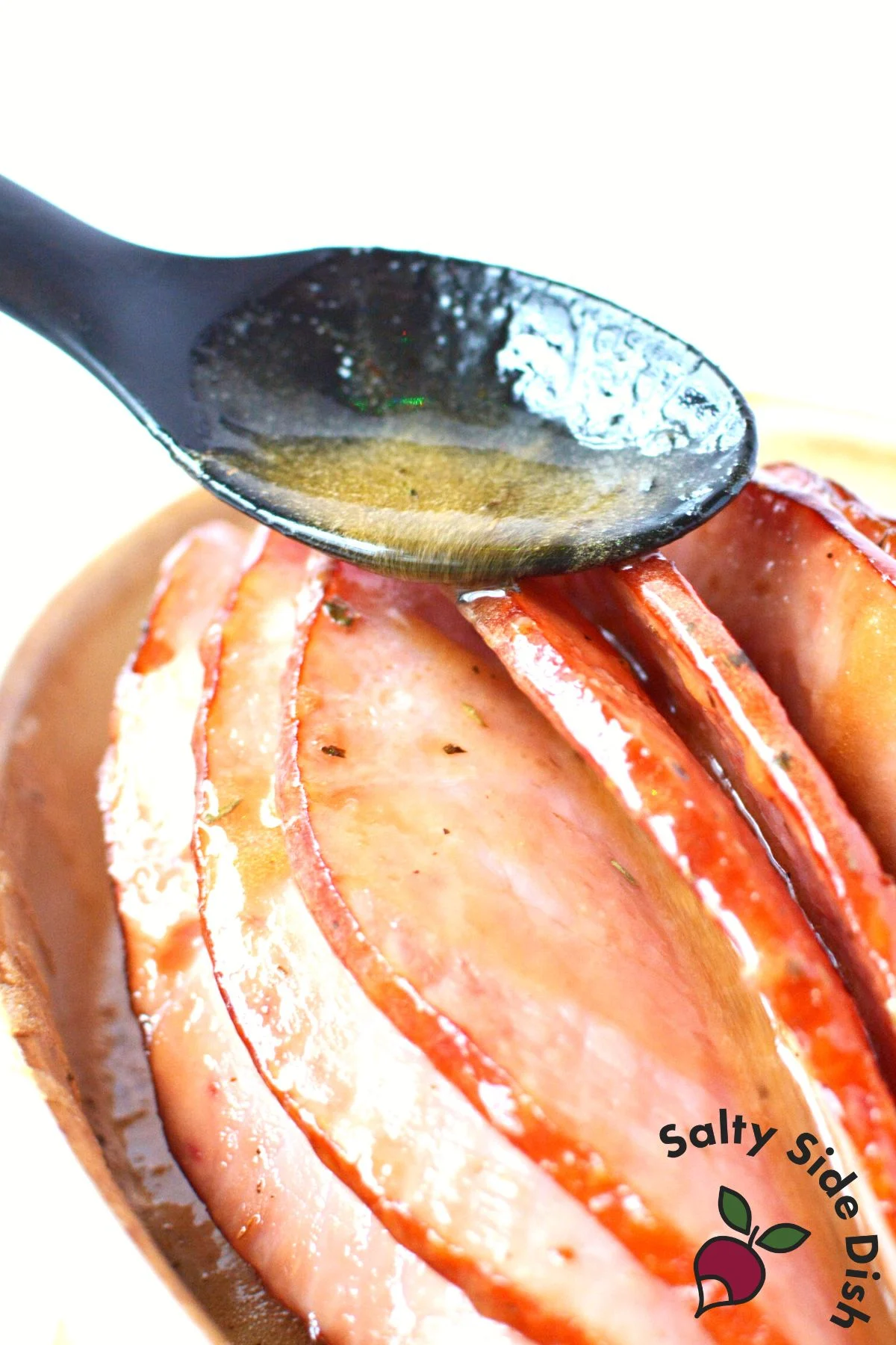 pouring glaze with spoon into spiral ham.