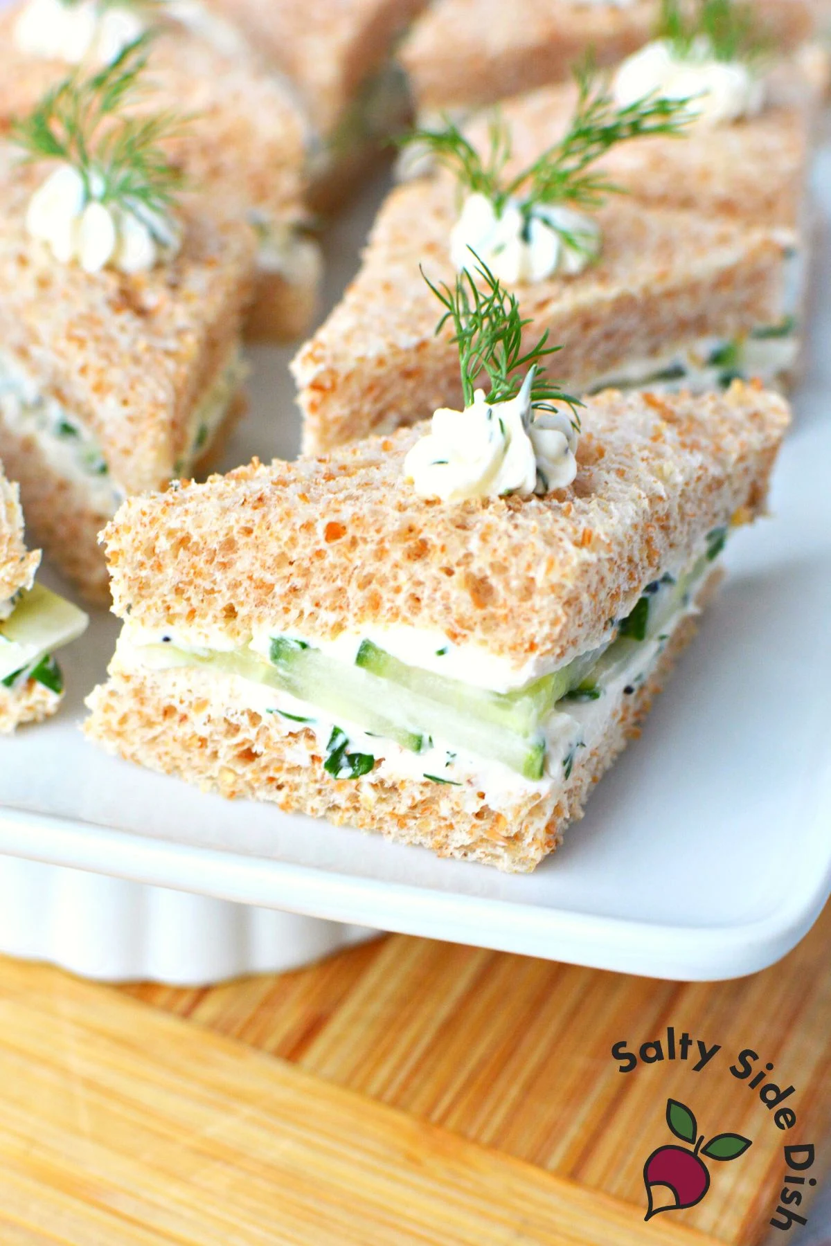 triangle cucumber sandwiches on a white plate.