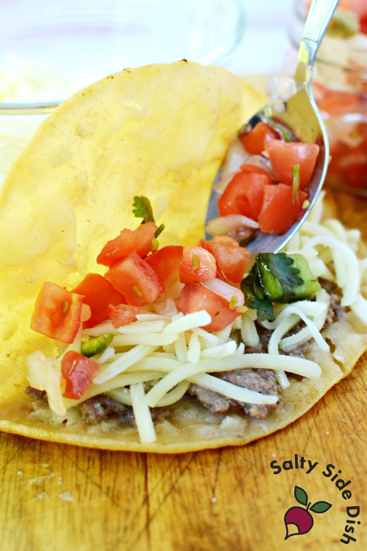 Close up of crispy fried beef taco filled with cheese and pico de gallo
