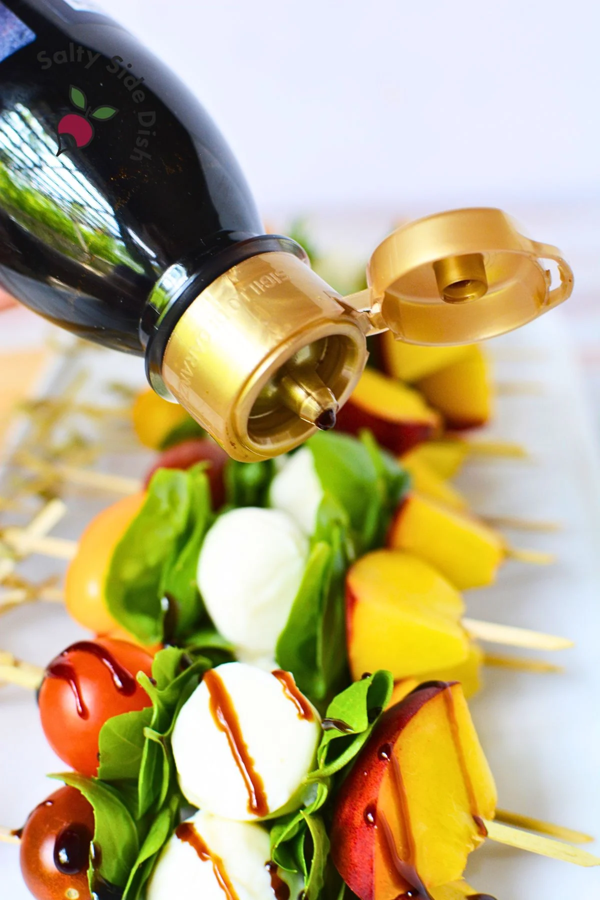 balsamic glaze from a bottle being poured over skewers.