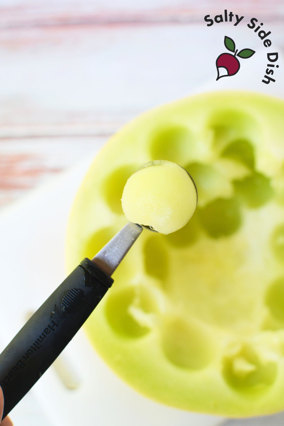 prepping honeydew melon into balls with a melon baller.