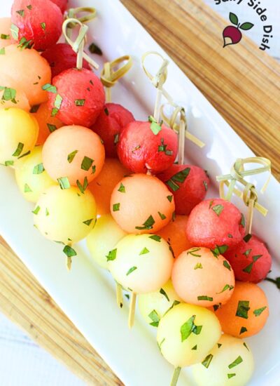melon ball fruit skewers on a white serving platter.