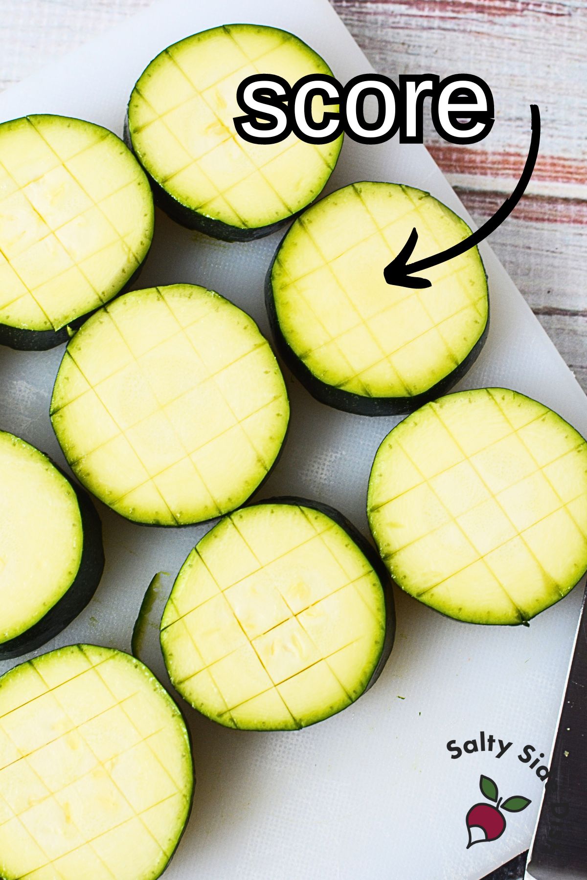 zucchini rounds on a cutting board scored in both directions.