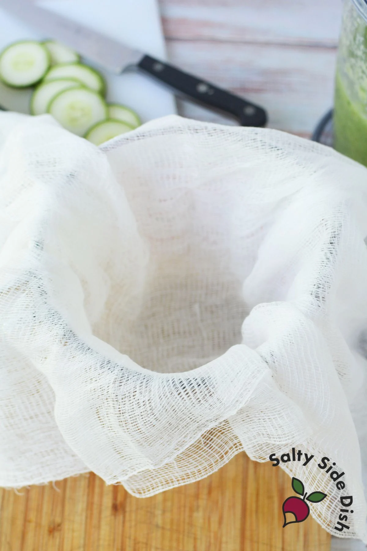 Straining cucumber pulp using cheesecloth to extract juice.
