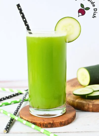 Freshly made cucumber juice in a glass with sliced cucumbers on the side..