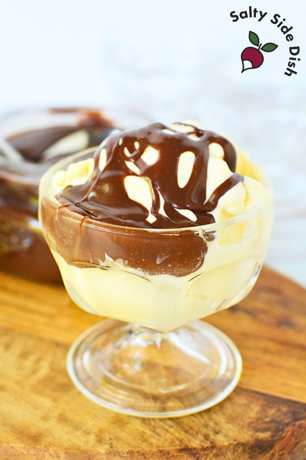drizzling of chocolate sauce over vanilla ice cream in a glass cup.