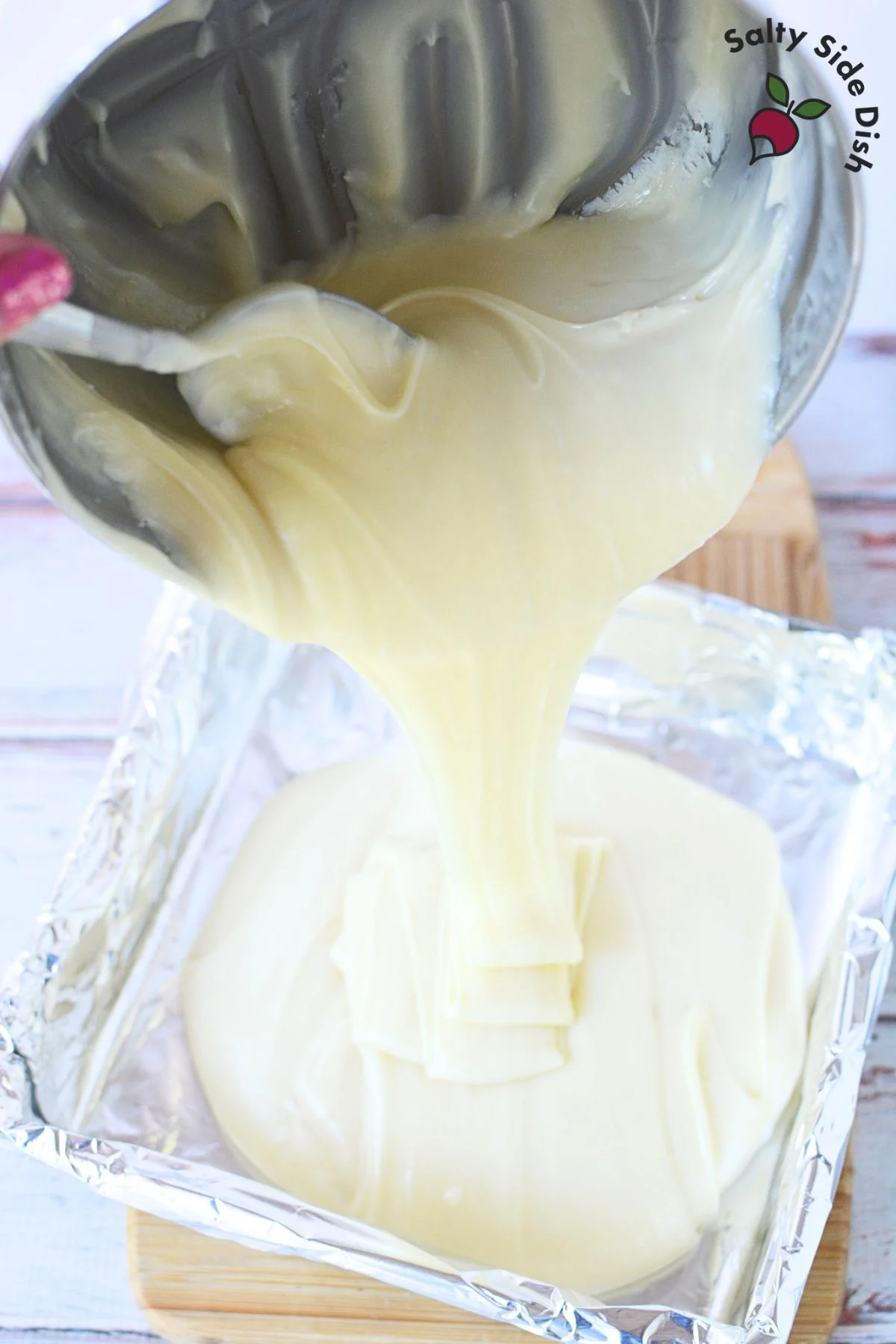 pouring white chocolate into a baking pan.