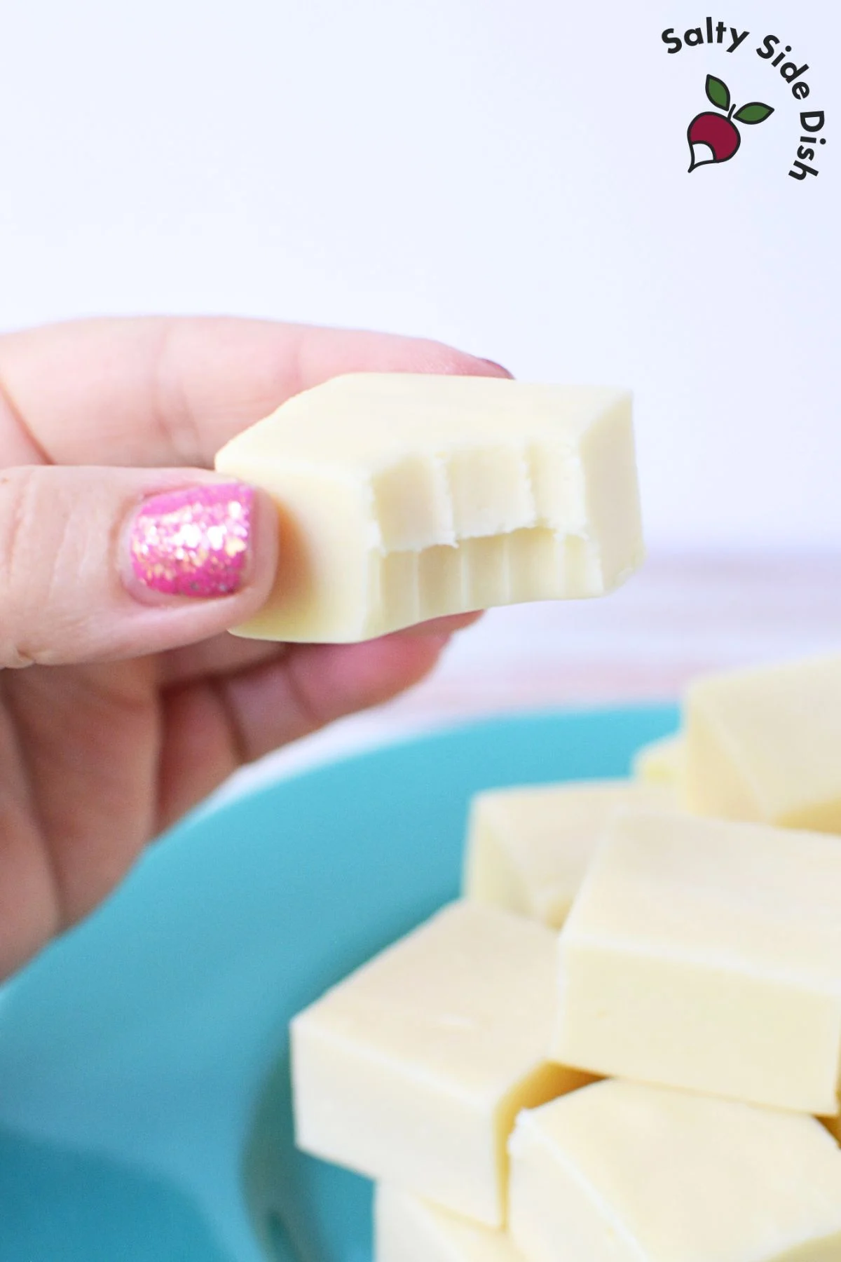 white chocolate fudge being held with bite out of it.
