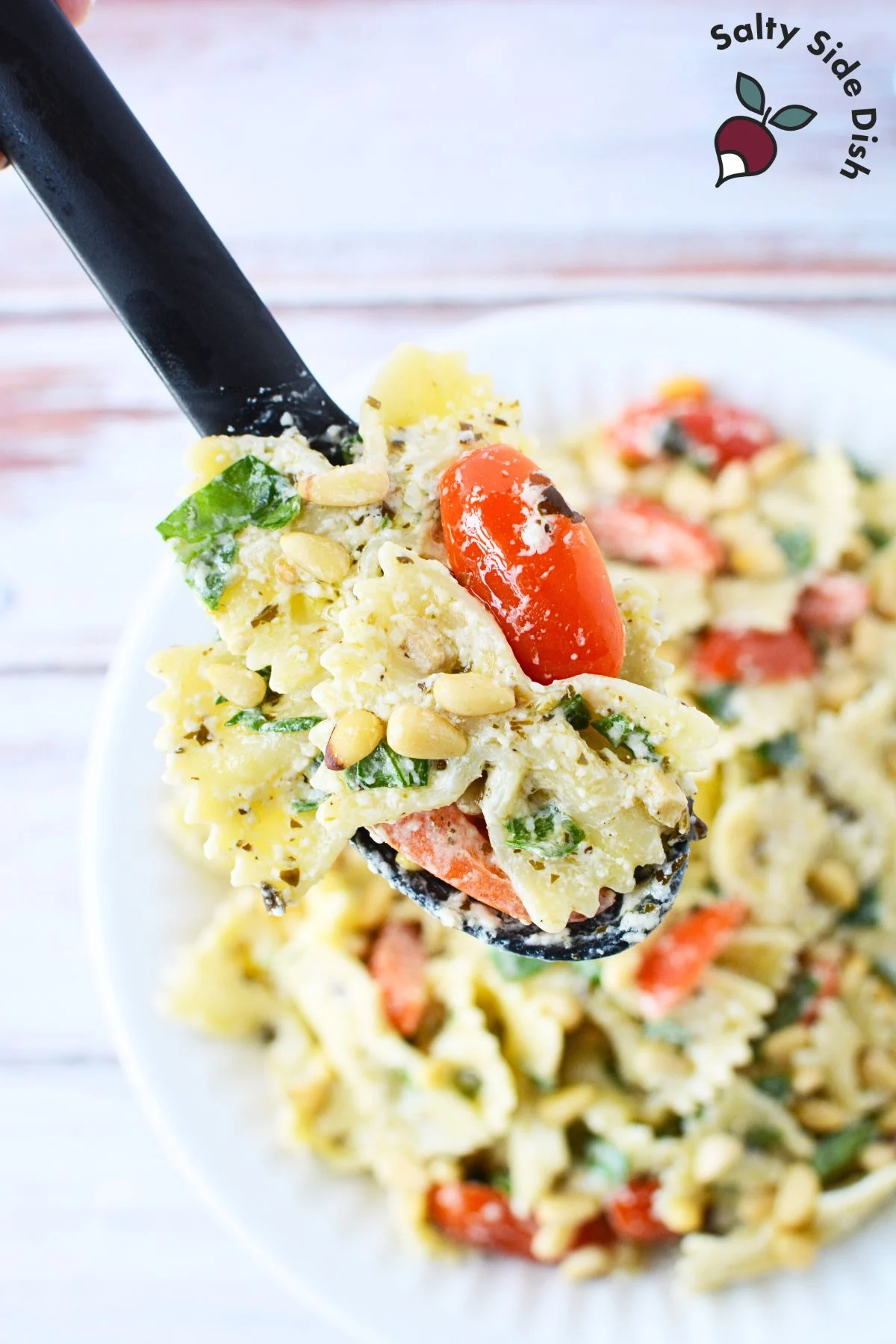Spoon of pasta salad with pesto dressing.