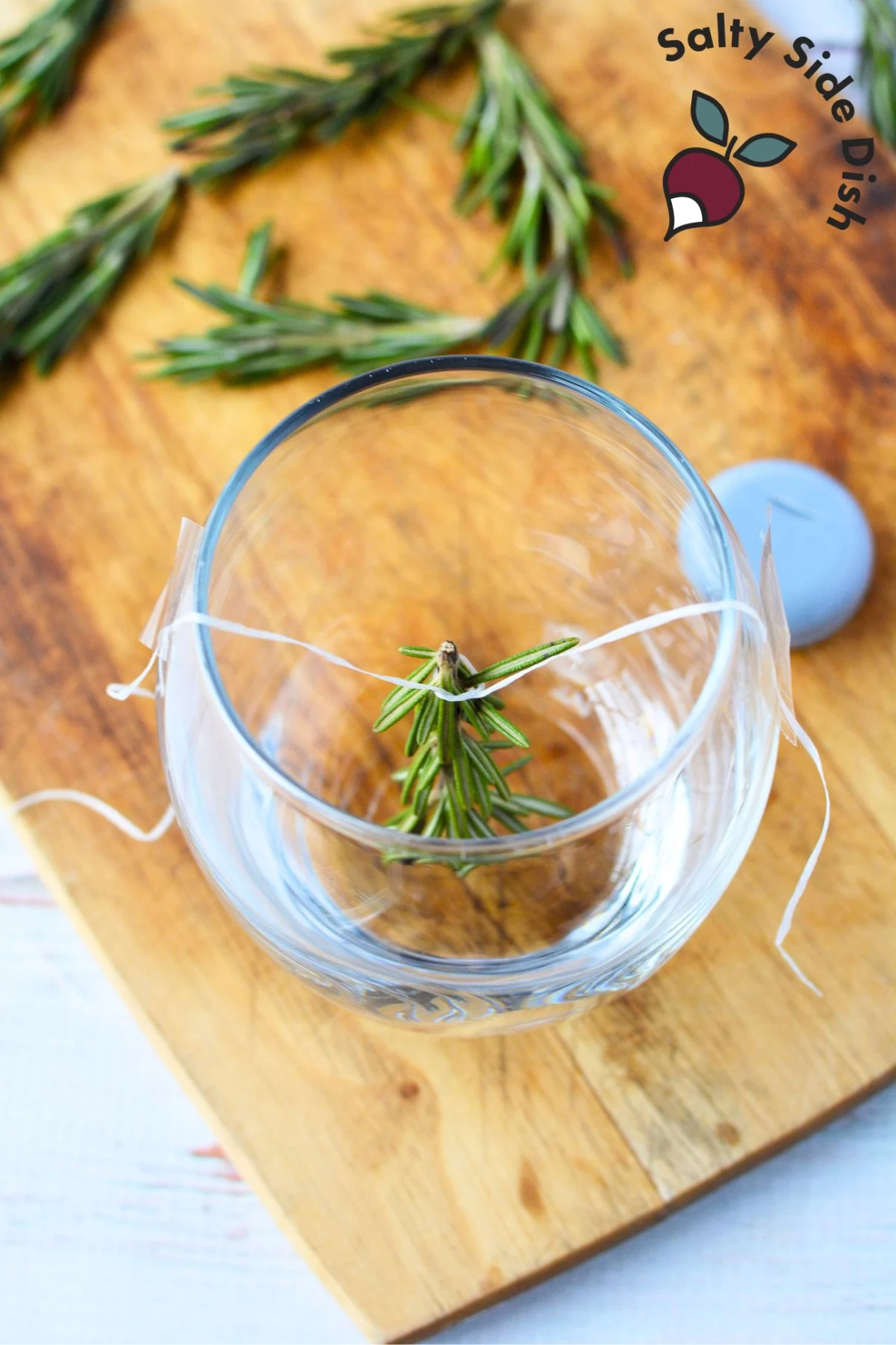 use tape to affix floss to sides of glass and hold rosemary up.