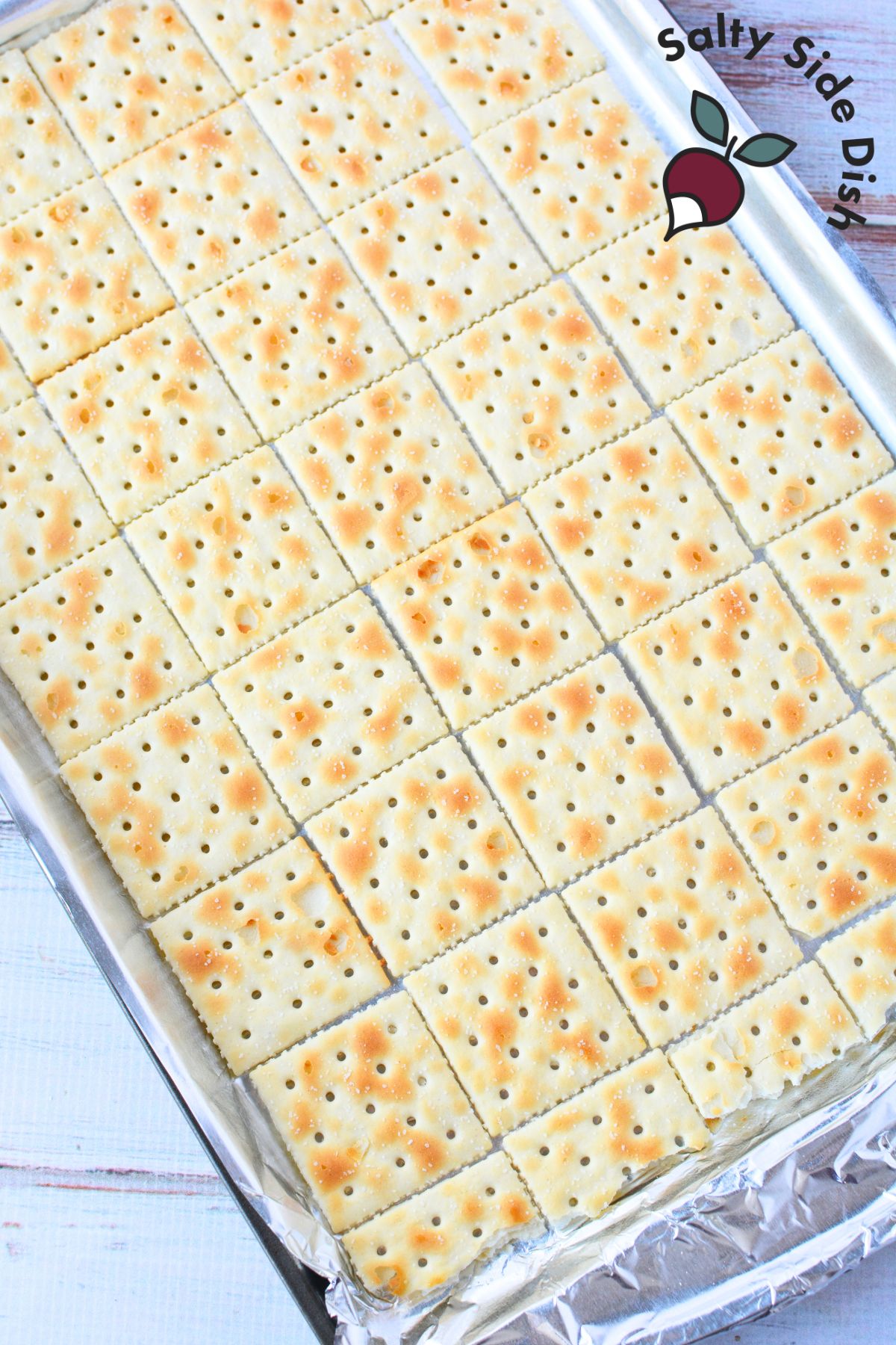 Saltine crackers arranged in a single layer on a foil-lined baking sheet, ready to be topped with homemade toffee.