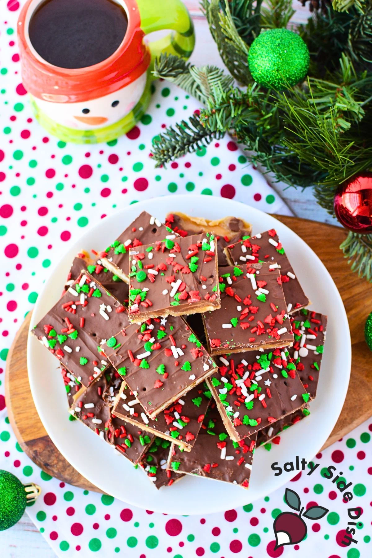 A tray of fully prepared Saltine Christmas Crack topped with chocolate and festive sprinkles, ready to be cut into pieces.