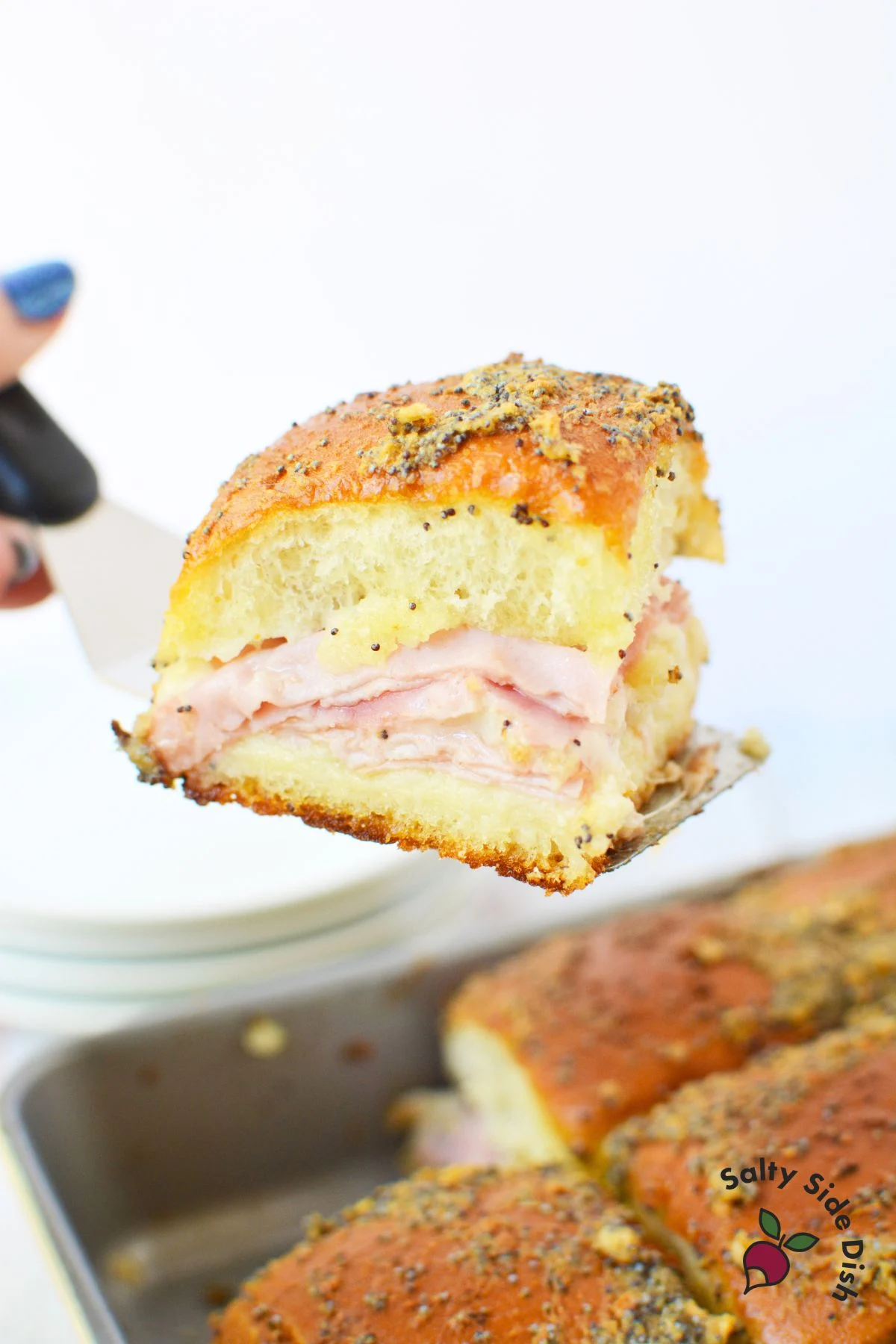 The best Ham and cheese sliders being pulled out of a baking pan.