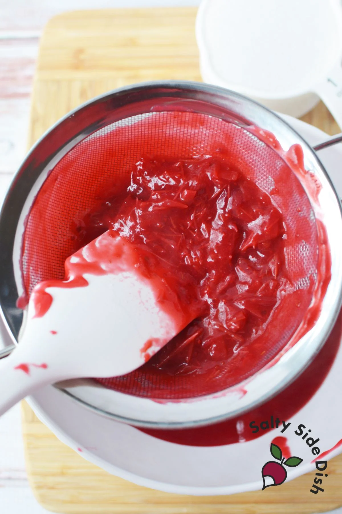 pushing cranberry sauce through sieve.