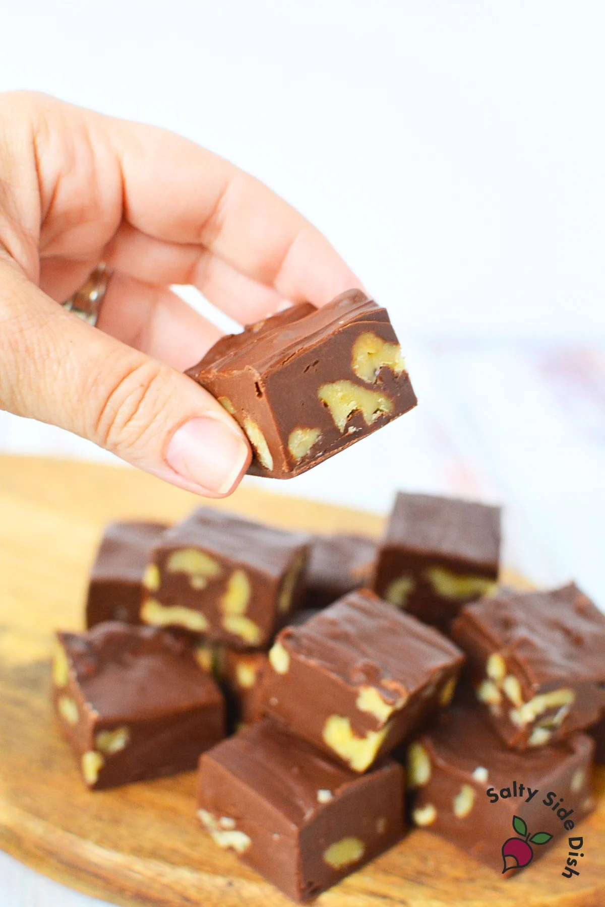 holding a fresh piece of chocolate microwaved fudge.
