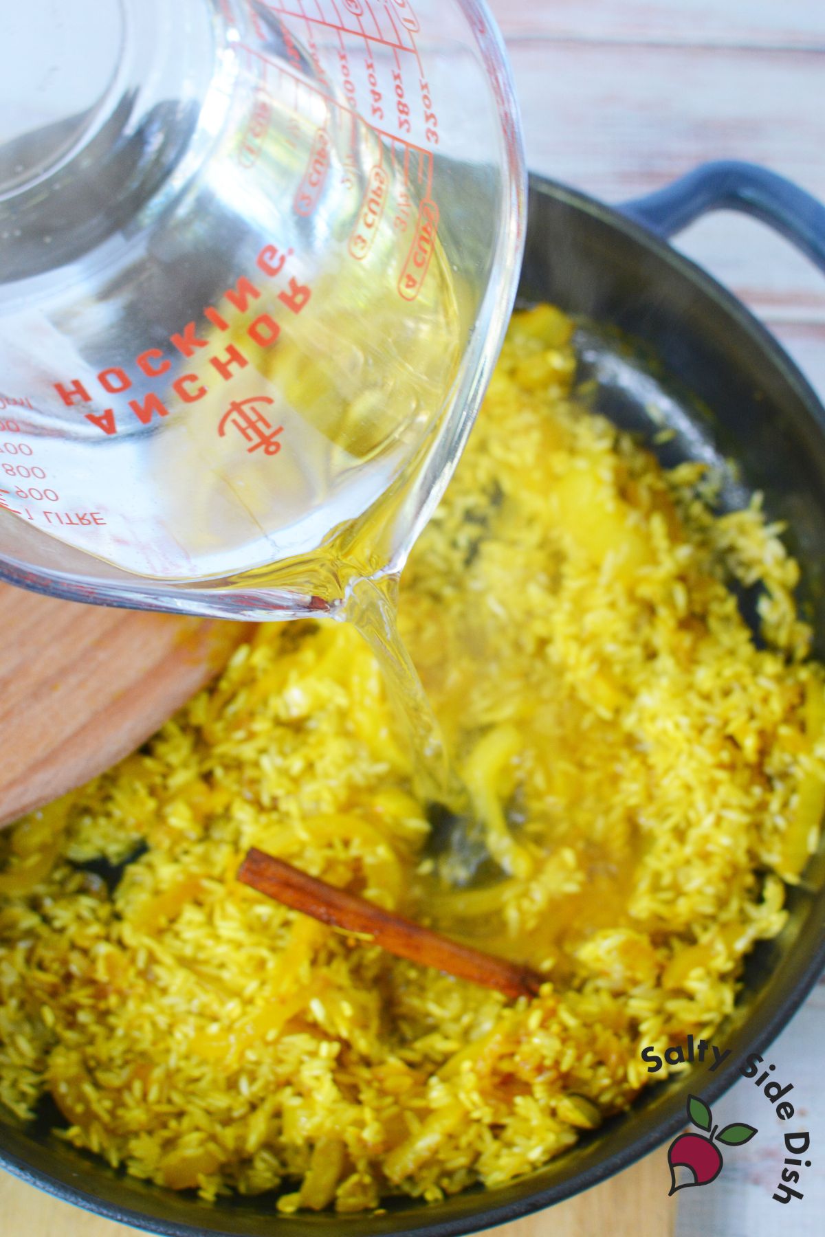 adding water to rice in a skillet.